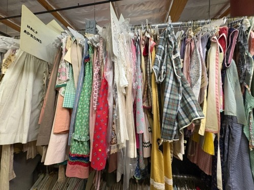 Collection of assored period half aprons and pinafore aprons and house coats.